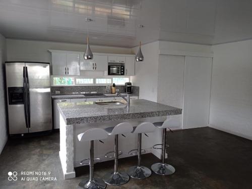 a kitchen with a counter with stools and a refrigerator at Villa las Águilas 1 in Borrero Ayerbe