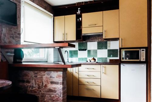 a kitchen with white cabinets and a brick wall at Viešnagė pas Valentiną in Sužionys