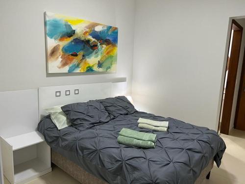 1 dormitorio con 1 cama con una pintura en la pared en Apartamento - Ubatuba - Toninhas - 350 passos da praia - 350 steps to the beach - Costa Verde en Ubatuba