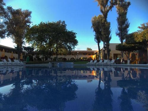 a pool of water with trees and white chairs at Casa Cantarranas in Tehuacán