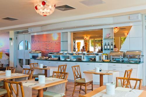 a restaurant with tables and chairs and a counter at Hotel Ambassador in Bibione