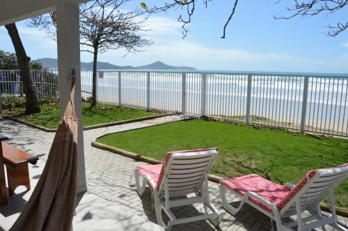 2 sillas y una hamaca en un patio con vistas al agua en Belíssima Casa - Pé na areia - Bombinhas - Canto Grande, en Bombinhas