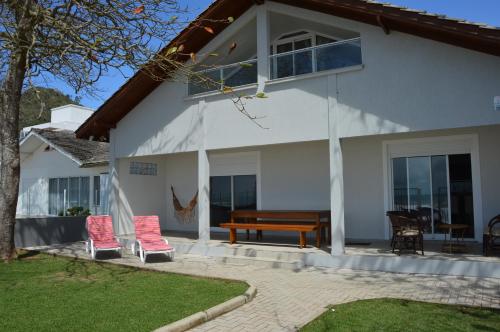 Casa blanca con 2 sillas y un banco en Belíssima Casa - Pé na areia - Bombinhas - Canto Grande, en Bombinhas