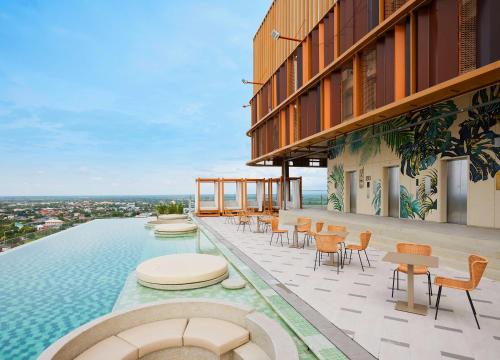 a pool on top of a building with chairs and tables at Centara Korat in Nakhon Ratchasima