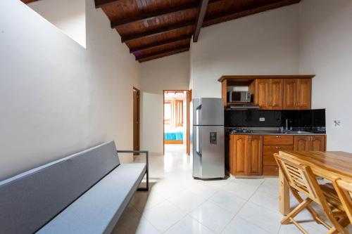 a kitchen with a bench and a table and a refrigerator at Apartamentos Primavera in Jardin
