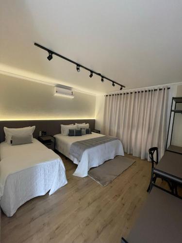 um quarto com 2 camas e lençóis brancos em Casa Bem Vino em Bento Gonçalves