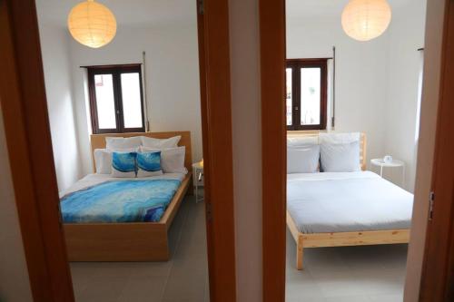 a bedroom with two beds and two windows at House in the historic area of Lourinhã in Lourinhã