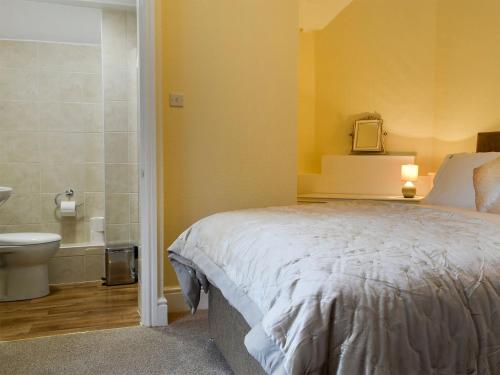 een slaapkamer met een bed en een badkamer met een toilet bij The East Wing At Grove Hall in Bodfari