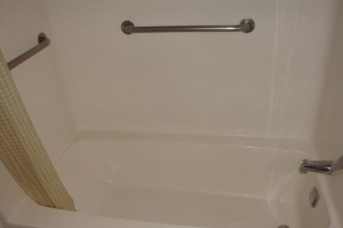 a white bath tub with a towel bar in a bathroom at American Motel in San Antonio