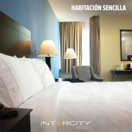 a hotel room with a white bed and a chair at Intercity Hotels San Pedro Sula in San Pedro Sula
