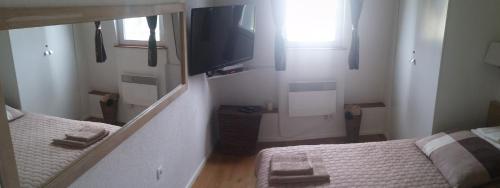 a bedroom with two beds and a tv and a mirror at Apartman Ena in Vlasic