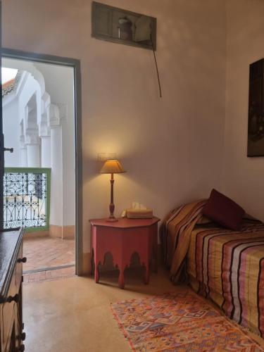 a bedroom with two beds and a table with a lamp at Riad Herougui in Marrakesh