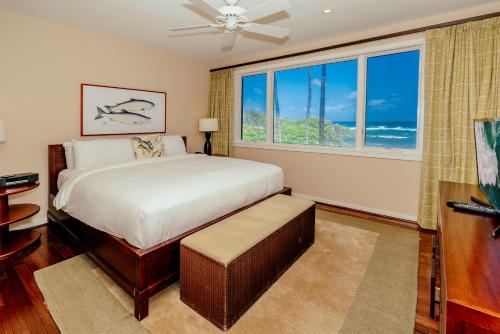 a bedroom with a bed and a large window at Turtle Bay Villas in Kahuku