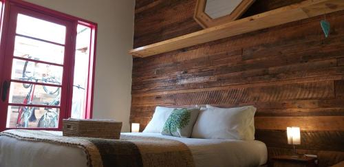 a bedroom with a wooden wall with a bed and a window at Treehouse Patagonia in Puerto Natales