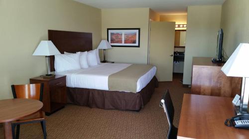 a hotel room with a large bed and a table at Southern Inn & Suites Lamesa in Lamesa