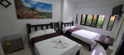 a bedroom with two beds and a painting on the wall at HOTEL CONTINENTAL.M in Puerto Boyacá