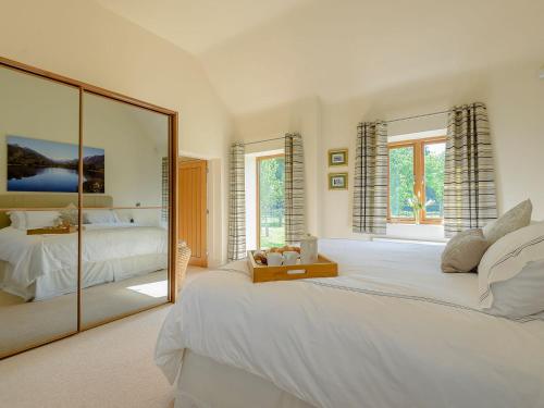 a bedroom with a large white bed and a mirror at Courtyard Lodge in Edwinstowe