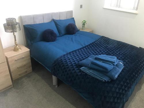 Una cama con sábanas azules y toallas azules. en Executive Apartment Central Doncaster en Doncaster