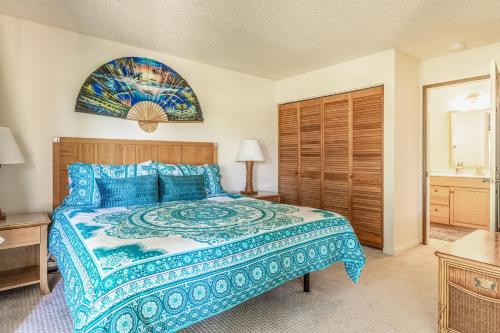 a bedroom with a large bed with a blue bedspread at Hale Honu in Waikoloa Village