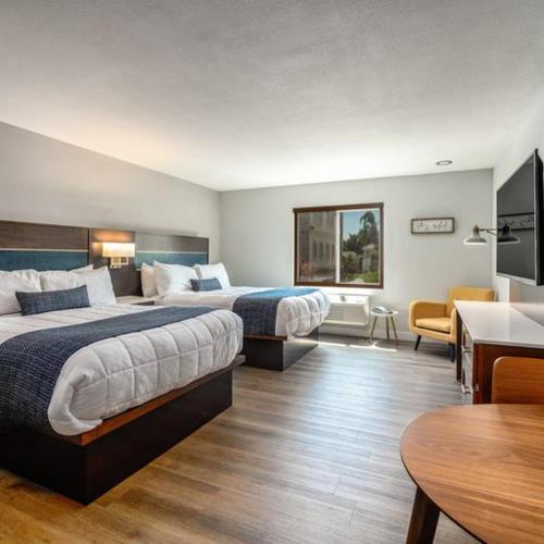 a hotel room with two beds and a table at Homestay Suites - Studios & Spas in Moreno Valley