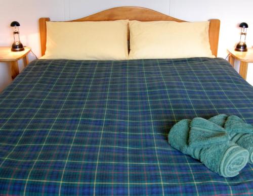 a bed with a plaid blanket and two towels on it at Carisbrook Cottage Queenscliff in Queenscliff