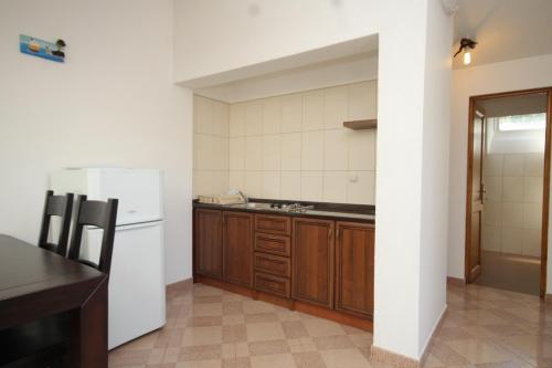 a kitchen with a white refrigerator and wooden cabinets at Seaside secluded apartments Cove Karkavac - Scedro, Hvar - 8801 in Jelsa