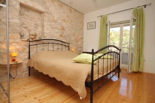 a bedroom with a bed and a stone wall at Seaside secluded apartments Cove Karkavac - Scedro, Hvar - 8801 in Jelsa