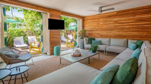 a living room with a couch and chairs and a tv at Kimpton Surfcomber Hotel, an IHG Hotel in Miami Beach