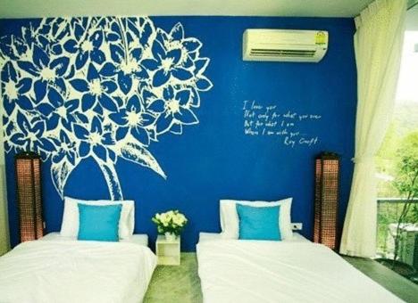 Duas camas num quarto com uma parede azul em White@Sea Resort em Ban Phe