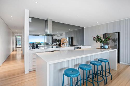 a kitchen with a white counter and blue stools at Louttit Bay Apartment 1 in Lorne