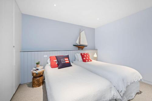 een slaapkamer met een groot wit bed met rode kussens bij Louttit Bay Apartment 1 in Lorne