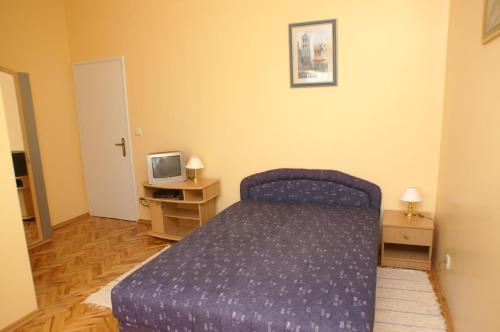 um quarto com uma cama roxa e uma televisão em Studio Vodice 4172d em Vodice