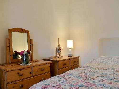 a bedroom with a bed and a dresser with a mirror at Spey Cottage in Aberlour