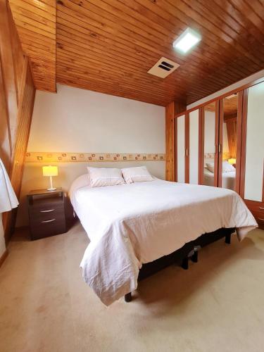 a bedroom with a large white bed with wooden ceilings at CORTEZ CASA in Ushuaia