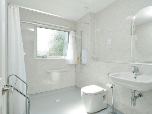 a bathroom with a toilet and a sink and a window at Westburn in Comrie