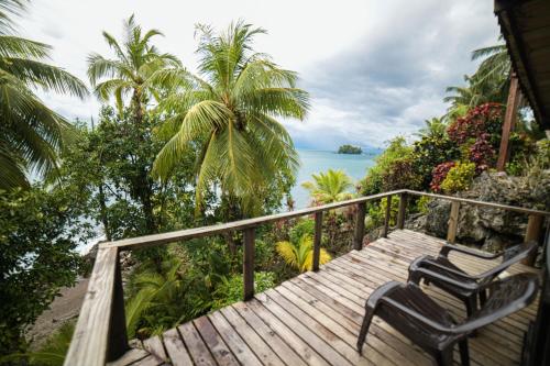 a wooden deck with two chairs and the ocean at Casa Balae in Nuquí