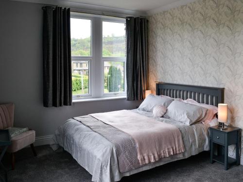 a bedroom with a bed with two lamps and a window at Glenfield in Keighley