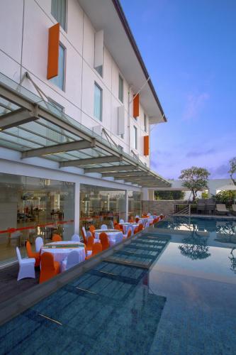 a hotel with a swimming pool with tables and chairs at HARRIS Hotel and Conventions Denpasar Bali in Denpasar