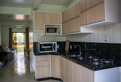 a kitchen with a microwave and a stove top oven at Residencial Elpidio in Bombinhas