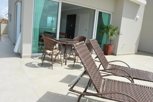 Un patio con sillas y una mesa en el balcón. en Belíssima cobertura duplex - De frente para o mar - Bombinhas-SC, en Bombinhas