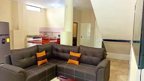 ein Wohnzimmer mit einem braunen Sofa und orangefarbenen Kissen in der Unterkunft Departamento la comodidad de tu casa in Machala