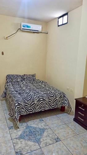Un dormitorio con una cama con una manta de cebra. en Departamento la comodidad de tu casa, en Machala
