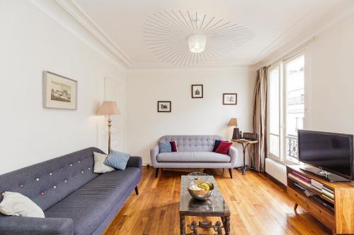 Large Apartment For A Family 2 Adults Max! في باريس: غرفة معيشة مع أريكة وتلفزيون