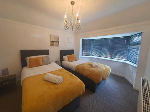 a bedroom with two beds and a chandelier at Stylish and homey 3 bedroom house with free parking & Wi-Fi in Minworth