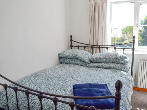 a bedroom with a bed with blue sheets and a window at Crown Courtyard Cottage in Grewelthorpe
