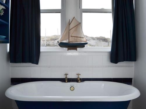 a bath tub in a bathroom with a sail boat in a window at Vindolanda in Fearnmore