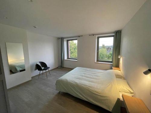 1 dormitorio con 1 cama, 1 silla y 2 ventanas en Attractive holiday home in Wallonie with garden en Gros-Fays