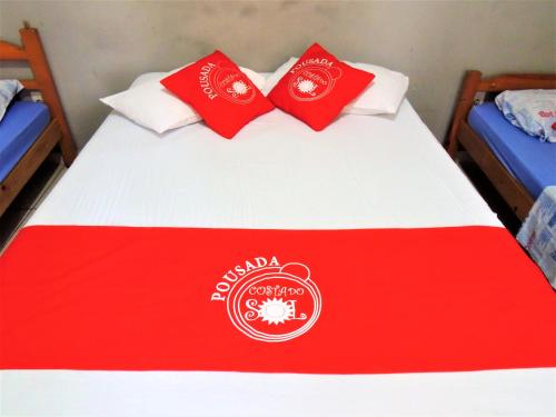 a bed with a red and white blanket on it at Pousada Costa Do Sol - By UP Hotel in Praia Grande