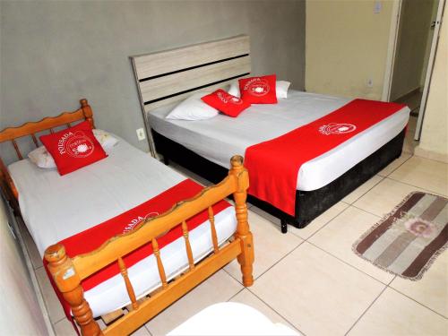 two beds with red and white pillows in a room at Pousada Costa Do Sol - By UP Hotel in Praia Grande