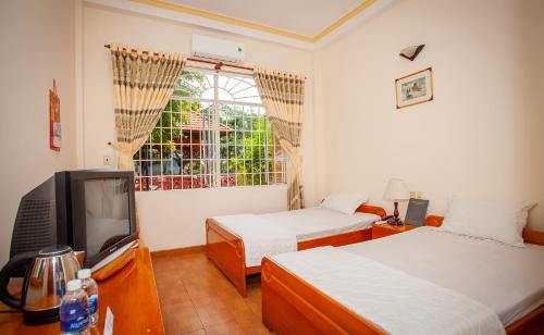 een slaapkamer met 2 bedden, een tv en een raam bij KHÁCH SẠN BẾN ĐÁ NÚI SAM in Chau Doc